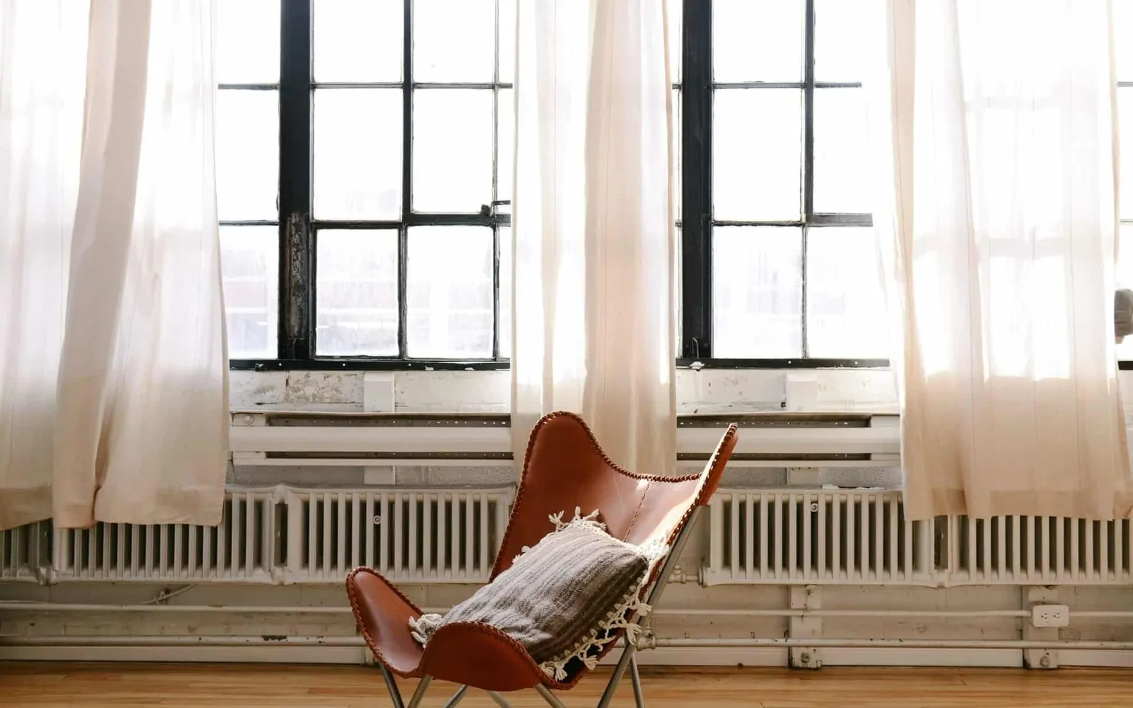 Intérieur lumineux, fauteuil en cuir et toile devant de hautes fenêtres