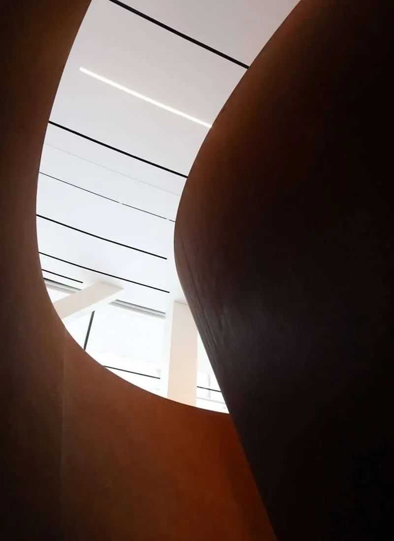 Courbe d’un escalier en bois baigné de lumière
